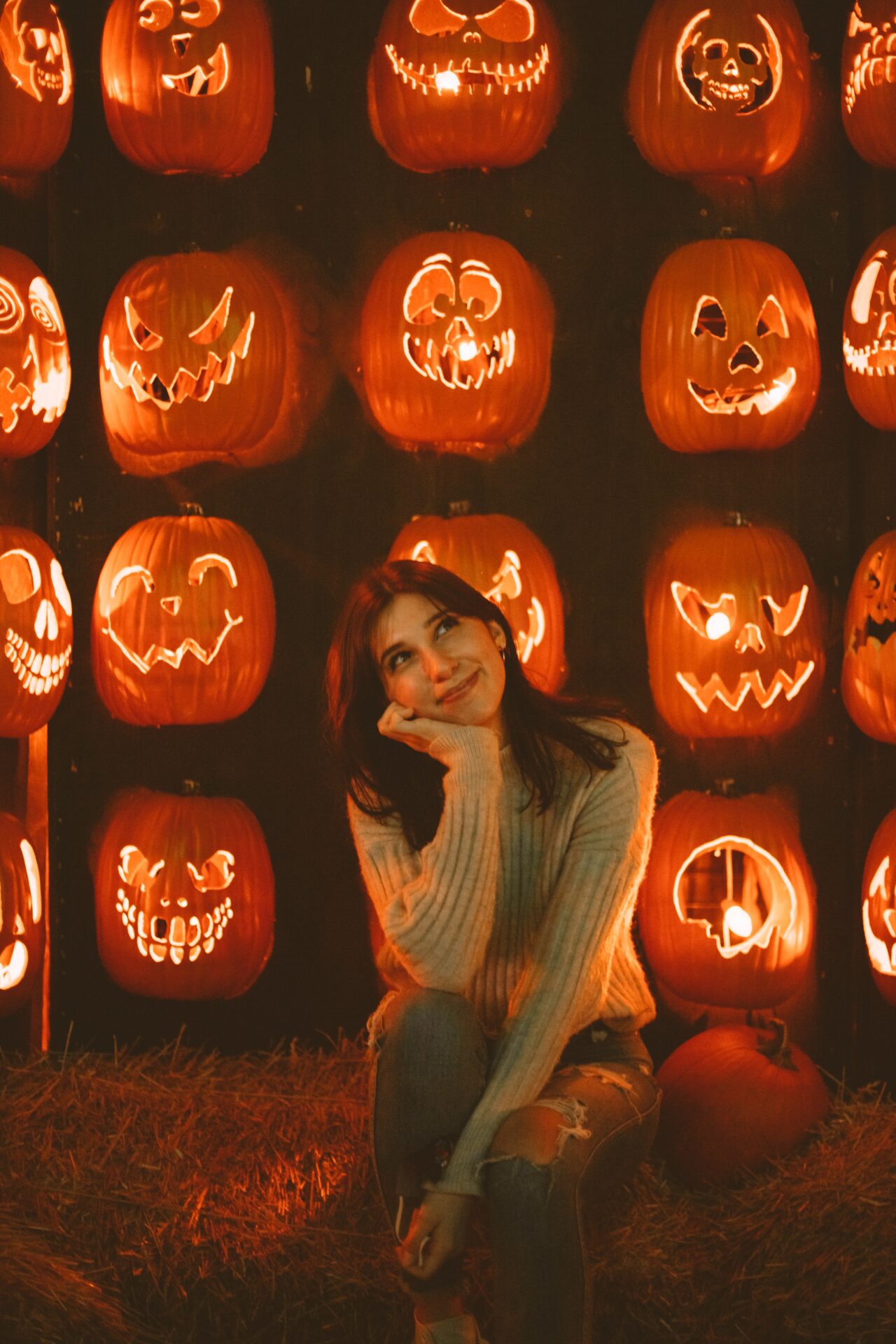 woman smiling with halloween pumpkins in the background