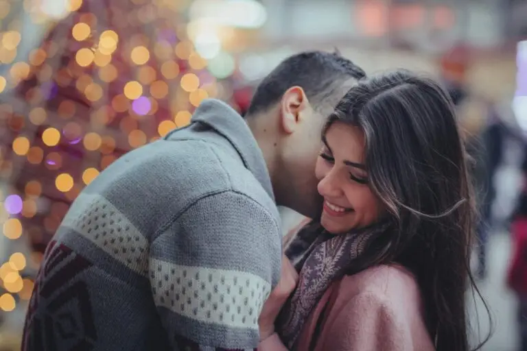 man leaning over and whispering in woman's ear